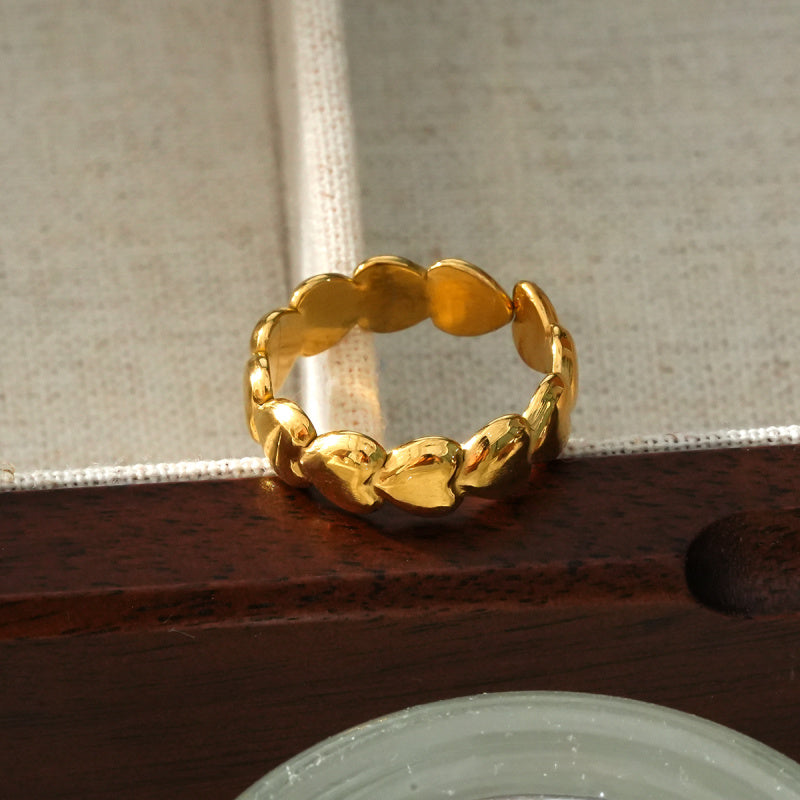 Anello regolabile dorato con cerchio decorato da cuori stilizzati.